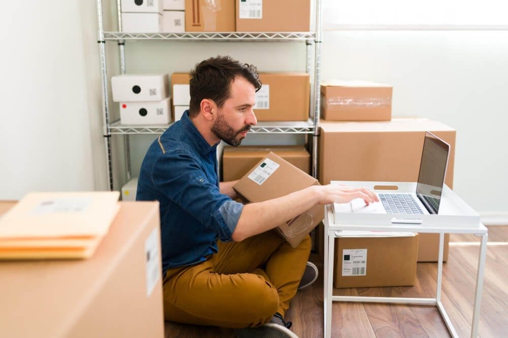 hispanic-young-man-sitting-his-office-floor-while-holding-package-typing-laptop-check-customer-order-from-online-shop-1.jpg